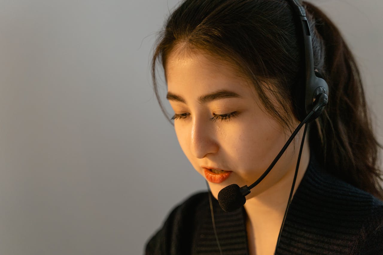 gallery-01 Focused young woman in headset working in customer support, speaking attentively.
